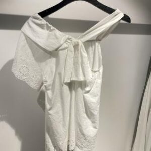 Blusa blanca con escote asimétrico y moño lateral