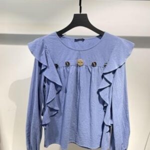Blusa azul con volantes en el pecho y botones decorativos